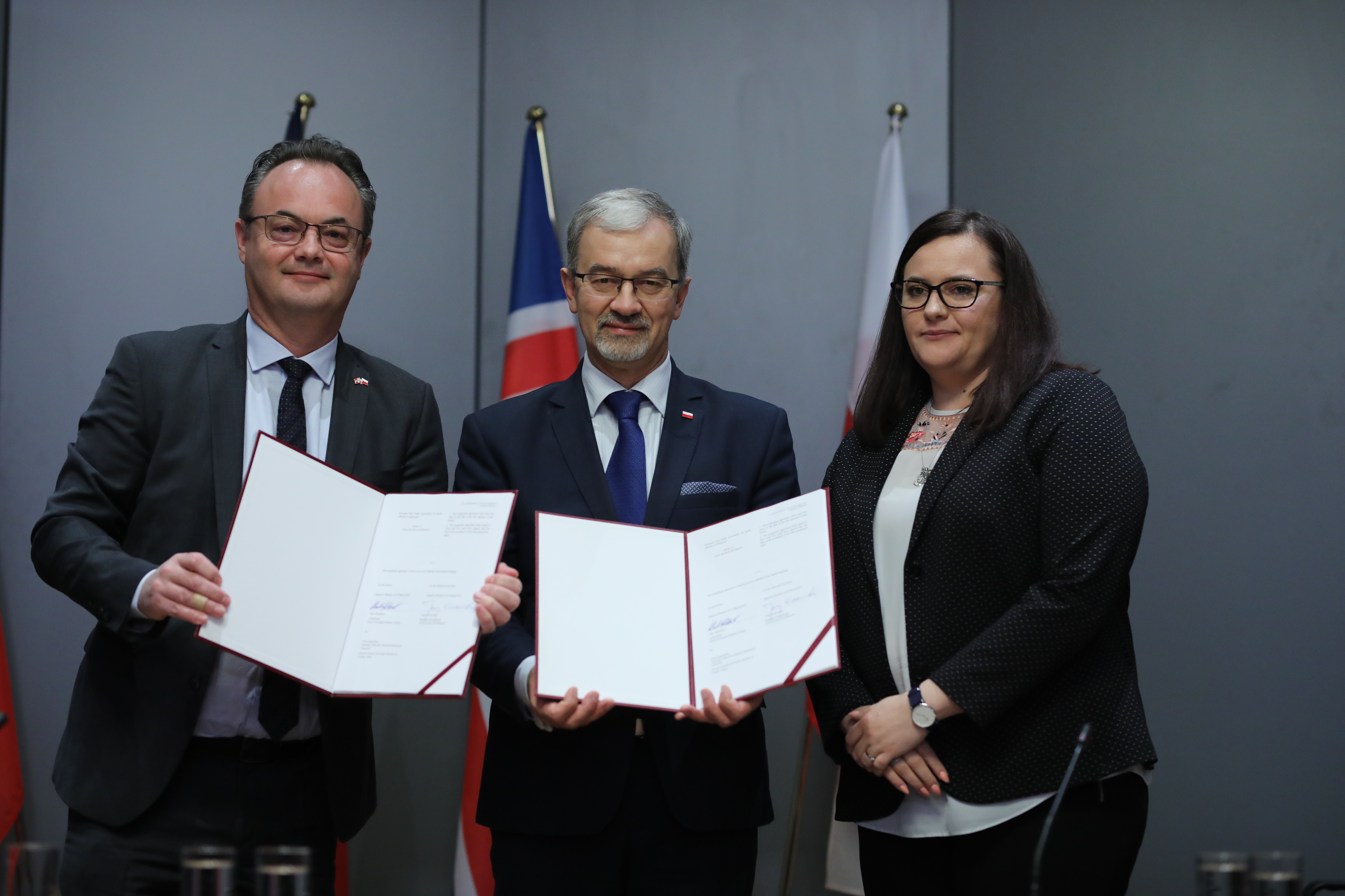 Minister Kwieciński stoi z ambasadorem Myklebustem oraz wiceminister inwestycji i rozwoju Małgorzatą Jarosińską-Jedynak. Minister i ambasador trzymają w dłoniach podpisane umowy. 